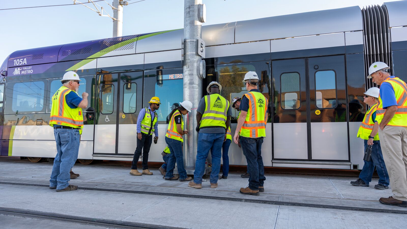 Track personnel wearing protective equipment near a light rail train